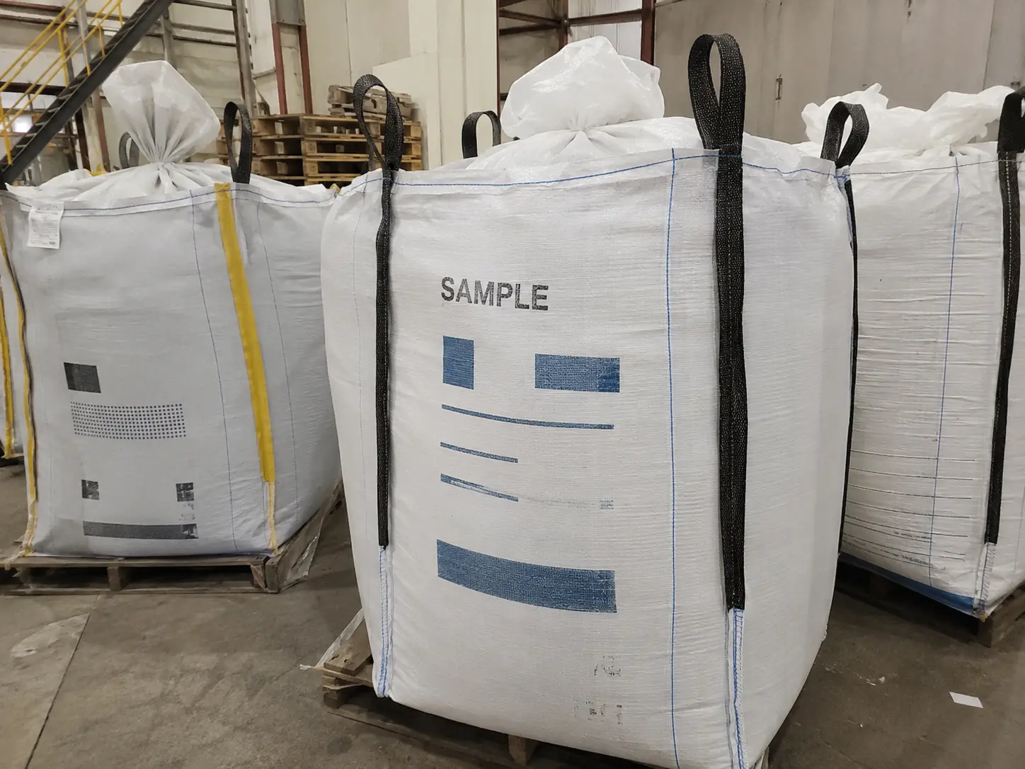 Several FIBC bulk bags of different specifications — plain, printed, and lined — side by side on a factory floor